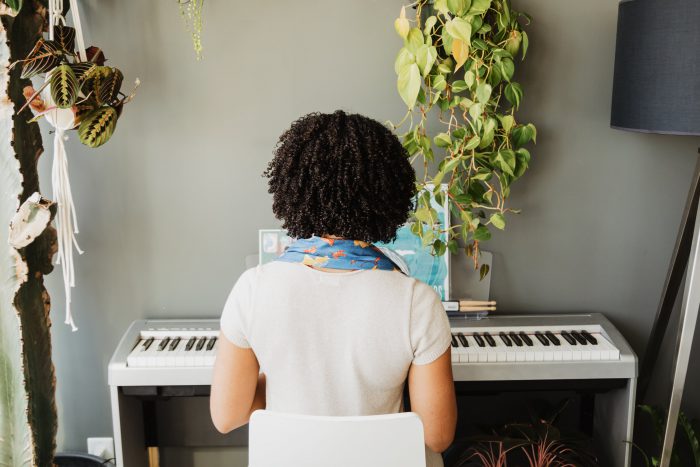 A woman plays her white keyboard near the window