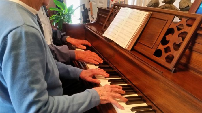 two men at piano with sheet music