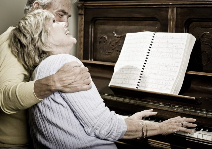 older couple at piano laughing