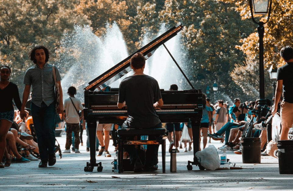 Man playing piano in the middle of a busy park