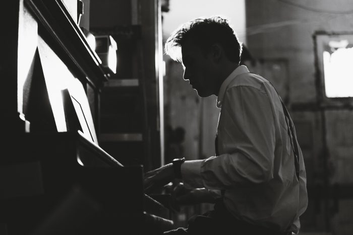 younger man playing upright piano