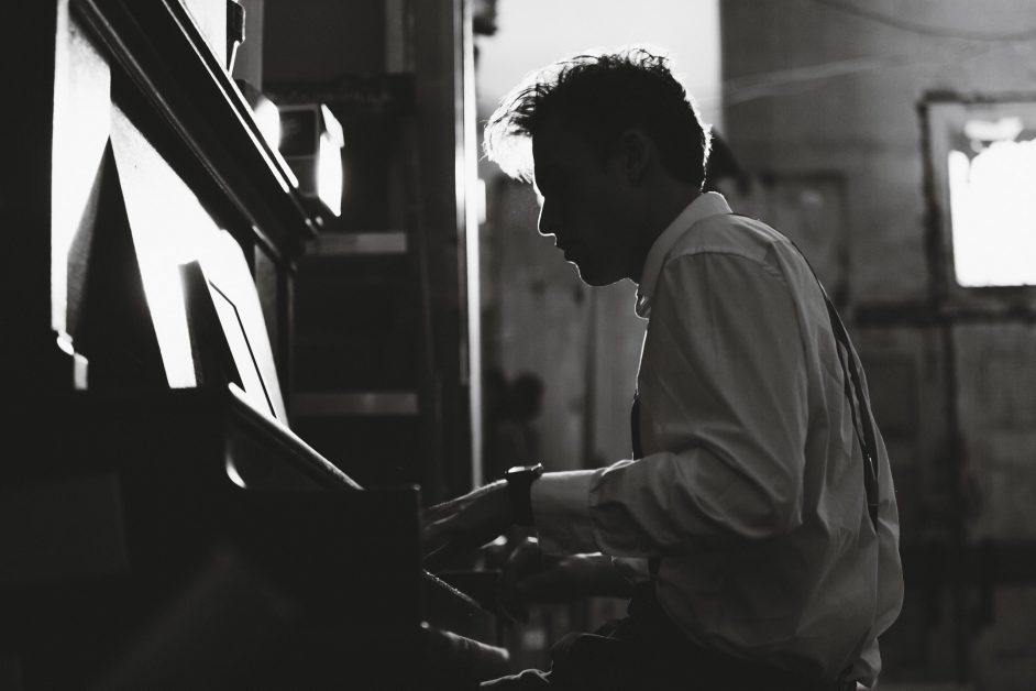 younger man playing upright piano