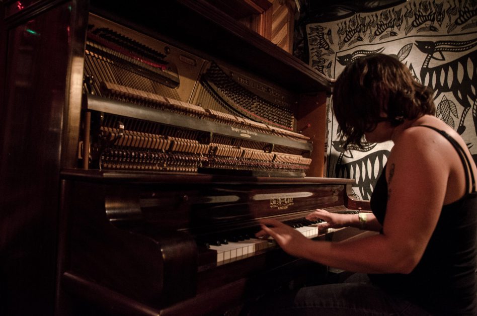 woman in black tank top playing the piano