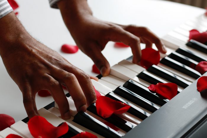 red rose petals on a white keyboard while someone is playing